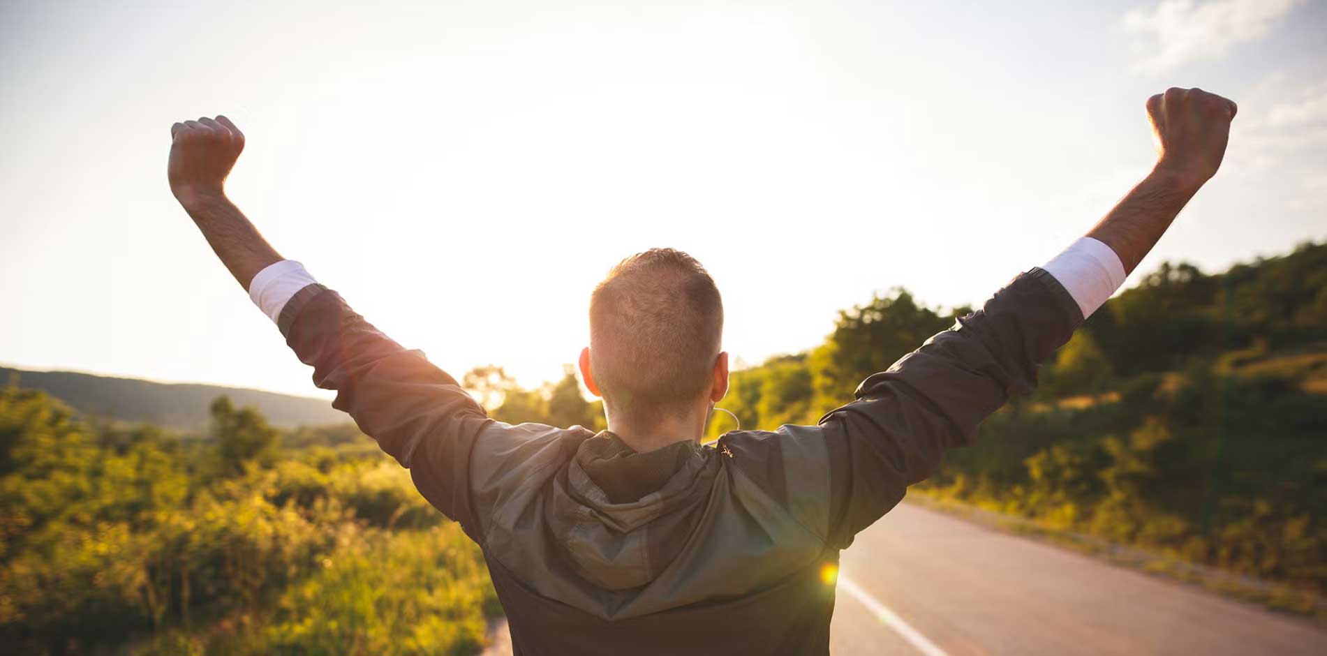 man celebrating in front of sunset
